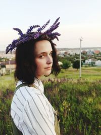 Portrait of young woman standing on field against sky