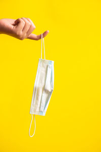 Cropped hand holding cleaning equipment against yellow background