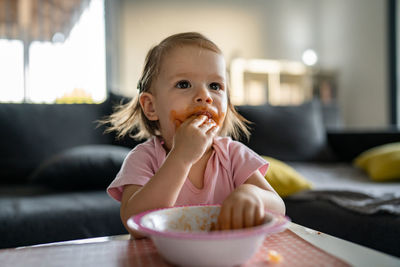 Portrait of young woman eating food on table