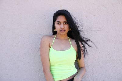 Portrait of beautiful young woman standing against wall