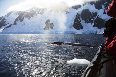 Scenic view of snowcapped mountains by sea on sunny day