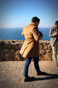 Rear view of friends standing on rock against sea