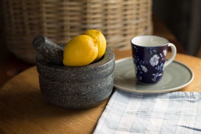 Close-up of lemons on mortar by cup and saucer