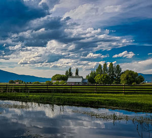 Scenic view of pond by building against sky