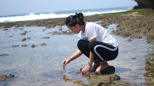 Full length of woman crouching at beach