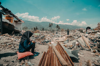 PANORAMIC VIEW OF MAN SITTING ON WOOD AGAINST SKY