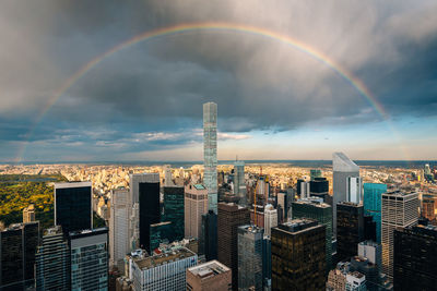 Aerial view of rainbow over buildings in city against sky