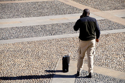 Full length rear view of man standing on street during sunny day