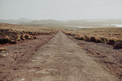 Road amidst agricultural field against sky