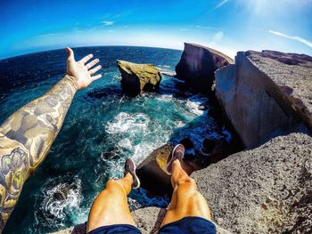 Low section of man in sea against blue sky