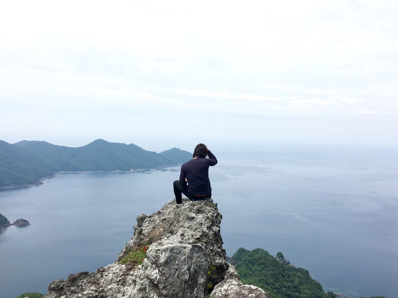 water, mountain, lifestyles, tranquil scene, standing, tranquility, leisure activity, scenics, beauty in nature, sky, rear view, sea, nature, getting away from it all, full length, looking at view, rock - object, three quarter length