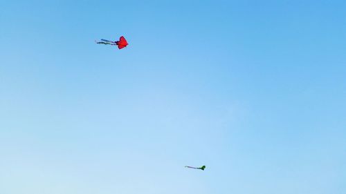 Low angle view of kites flying against clear sky