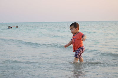 Cute boy walking in sea at beach