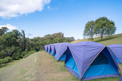 Deck chairs on field against blue sky