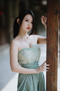 Portrait of young woman standing against wall