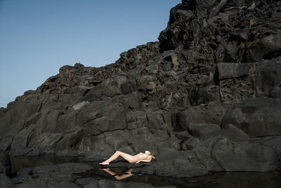 Low angle view of woman on rock against sky