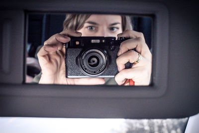 Woman photographing reflection on car mirror