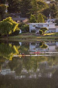 People kayaking in lake against houses