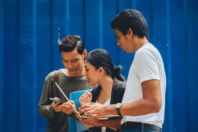 Friends looking away while standing on blue smart phone