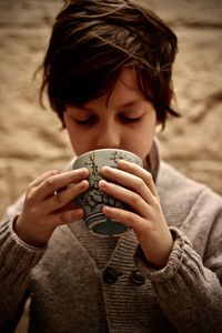 Close-up of boy wearing warm clothing while holding cup