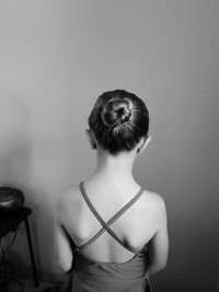 Rear view of woman with hair bun standing against wall