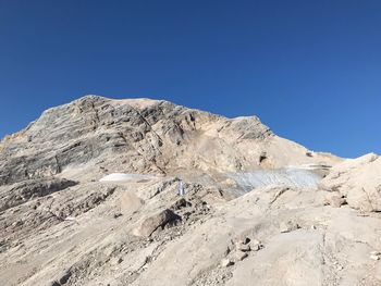 Low angle view of snowcapped mountain against clear blue sky