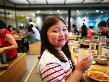 Portrait of smiling girl eating food in restaurant