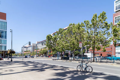 Trees by road against buildings in city