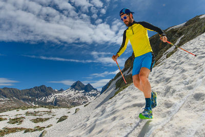 Low angle view of man standing on snowcapped mountain