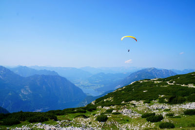 Low angle view of person paragliding over mountain against sky