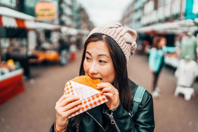 Portrait of woman eating food in city