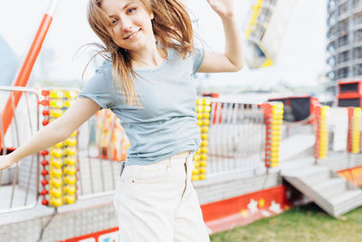 Happy young gen z woman in an amusement park jumping and smiling