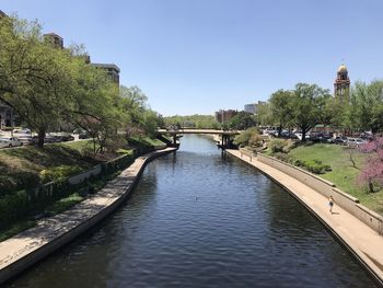 Canal amidst trees against clear sky