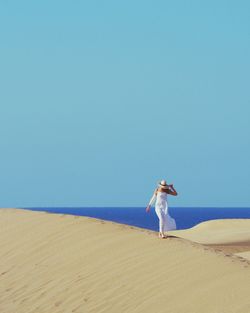 Woman on beach against clear sky