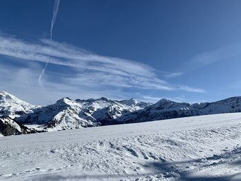 Scenic view of snowcapped mountains against blue sky