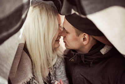 Close-up of couple kissing under blanket