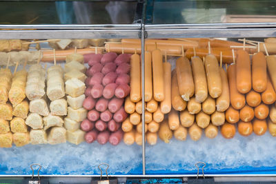 Raw sausages and meat arranged in display cabinet for sale at market