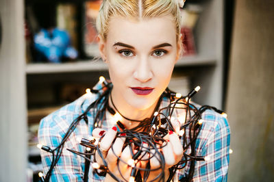 Portrait of young woman holding illuminated lights