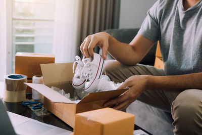 Midsection of man sitting on table at home