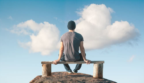 Rear view of man looking at rock against sky