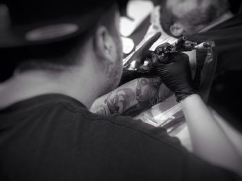 High angle view of man making tattoo on male customer arm
