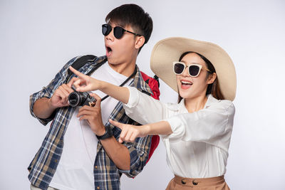 Young man holding sunglasses against white background