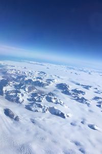 Aerial view of snowcapped landscape against blue sky