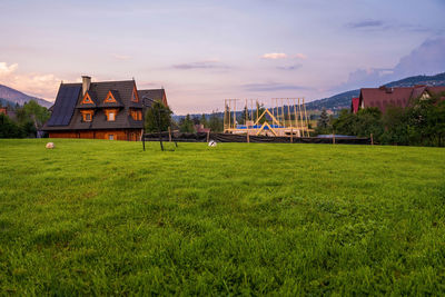 A football grass field against an under construction house located in a nature on mountains