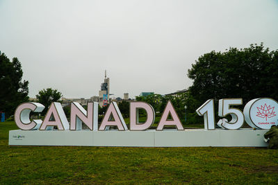 Information sign on grass against sky