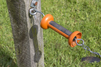 High angle view of orange handle attached to barbed wire fence on grassy field