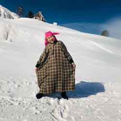 Portrait of smiling woman in traditional clothing standing on snow covered field