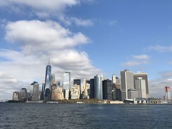Sea by modern buildings against sky in city