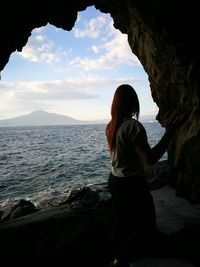 Side view of young woman standing at beach in cave