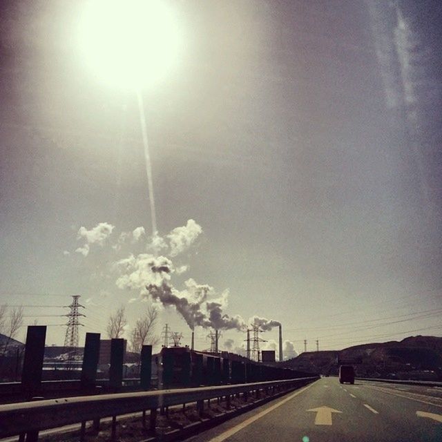 road, street light, transportation, the way forward, sky, built structure, architecture, building exterior, road marking, sun, diminishing perspective, street, sunlight, sunbeam, vanishing point, car, city, low angle view, outdoors, no people